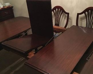 Mahogany dining room table, 5 armless chairs, one Captain’s chair, pads, 2 leaves
