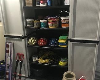 A garage cabinet holds a variety of items for sale and the cabinet is also for sale. Also available are the flag in box, arms to transport bikes, crock and joint sealer. 