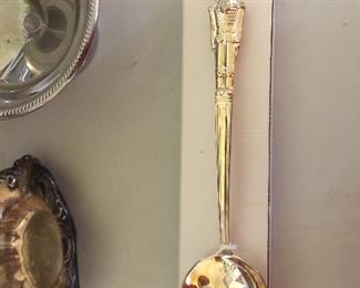 An usual slotted spoon topped with a soldier or nutcracker. 