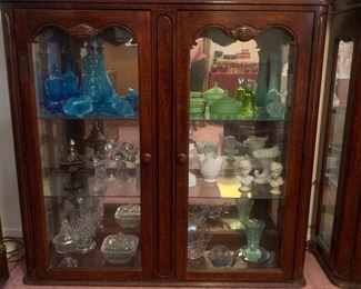 display curio cabinet with blue and green Fenton, milk glass and clear cut glasss