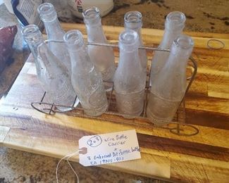 8 old embossed Dr Pepper bottles with wire carrier.  All have different writings on the base.  One is made by the Ball company, which took over the operations of the 3 Rivers Texas glass factory in the 1930s before closing it down. 
