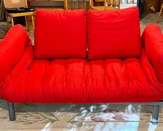 Red Futon Style Love Seat - can be used as a single bed - sides go down.