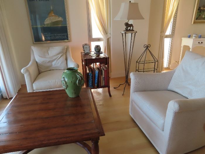 This is focal point this gracious condo. Featuring a pecan wood coffee table, Pair swivel club chairs , Canterbury style end tale. and the Majestic lion lamp In the background is a framed poster and a glass and metal 3 shelf curio .
