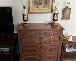 One of the dressers in the sale. To the left is a flat-screen TV. A pair of lamps that need shades.