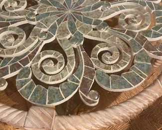 Close-up of glass top table with mosaic design in blues, greens, and tans