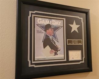 This framed tribute to the great Dallas Cowboys Coach Tom Landry includes a game day program cover from 1983, a plaque commemorating his placement in the Hall of fame and the Cowboys Ring of Honor, and an authentic autograph. Contains COA