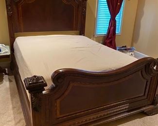 Beautiful Classic Queen Bed with Intricate Trim. It features four large posts with a layered base and swirled mahogany veneers