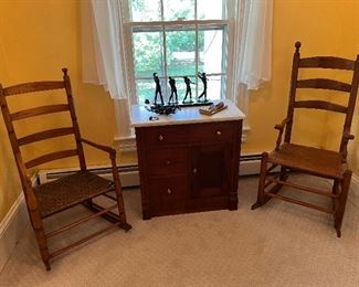 Duo of his and her's low wicker bottom ladder back rocking chairs
White Marble top vanity with brass drawer pulls


