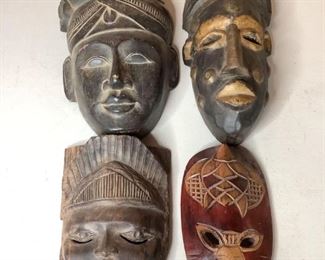 Four carved face masks. Includes (1) red and brown animal-like mask, H 8.5" x W 6", (1) black and gold mask, H 15" x W 6.5", (1) black solid face mask, H 13" x W 8" x D 3" and (1) dark brown mask, H 9" x W 7". All masks have some scratches and nicks.