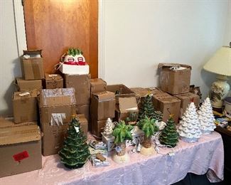 Table full of lighted Christmas porcelain trees and other accessories