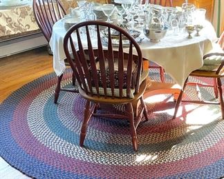 Round braided rug.  Six matching dining chairs with dark red paint on legs and backs. 