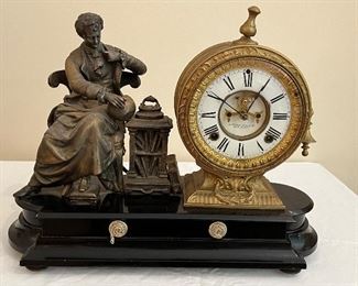 Antique Victorian Ansonia Decorative Figural Clock. This lovely clock is sold as-is with some condition issues. The chair the figurine is sitting on, has a broken leg in the back, there is not key and there is slight chip in the enamel on the face of the clock. Additionally, the top final is slightly loose.  Due to no key available, this clock was not tested. 

Measures 16" l x 14" h 