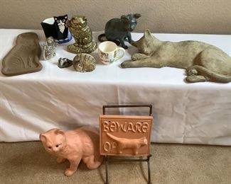 More than ten (10) items: Heavy lounging cat (broken paws), H 4.5" x W 18" x D 8", brass like cat door stop, H 7" x W 6" x D 2", brass like door stop, H 7" x W 6.5" x D 4", terra cotta cat (broken foot), H 12" x W 10" x D 8", terra cotta plaque on metal stand, H 14" x W 9" x D 8" & more (see photos).
