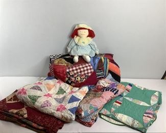 Approximately (5) quilts and (1) doll, most quilts appear to be handmade and unfinished in different patterns and colors.Largest is H 175" xW 93" and the smallest is H134"x W 86". Some may have tears or stains.Doll has red hair and blue dress with hat.