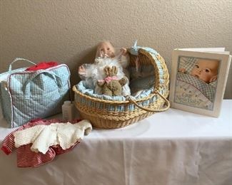 Book, basket, baby, and diaper bag full of clothes and accessories. Doll stored in plastic and has moveable eyes. Basket appears to be missing one handle. Book is torn on spline.