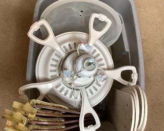 A large tub filled with what appears to be (2) ceiling fans, (1) is white with 21" white blades by Harbor Breeze, and (1) is brass colored (manufacturer's label not visible) with 22" wood-like blades, unknown working condition and if all parts are present.
