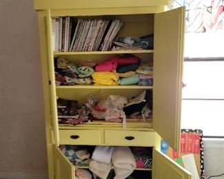 Large yellow hutch with fabric and sewing supplies