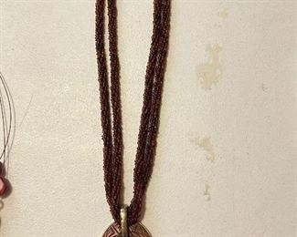 Brown multi-strand necklace with oval pendant, $10