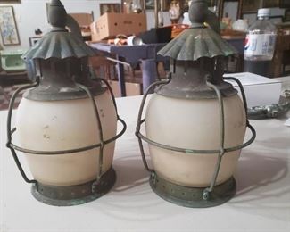 Old brass porch lantern light fixtures with the crinkled hat tops and wire cages.  Architectural