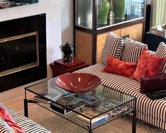 Two striped sofas, plush pillows, glass top table, and large display cabinet