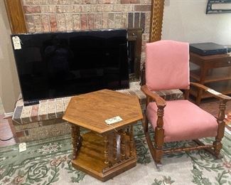 Flat screen tv, octagonal side table. Vintage pink wood rocking chair. 