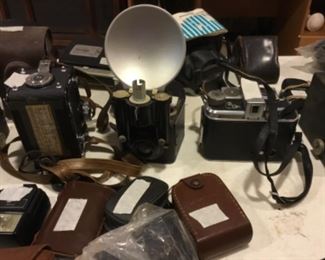 Downstairs- Table full of vintage cameras, binoculars, and movie cameras