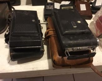 Downstairs- Table full of vintage cameras, binoculars, and movie cameras