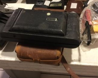 Downstairs- Table full of vintage cameras, binoculars, and movie cameras