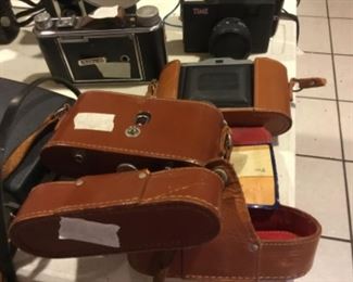 Downstairs- Table full of vintage cameras, binoculars, and movie cameras