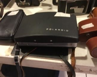 Downstairs- Table full of vintage cameras, binoculars, and movie cameras