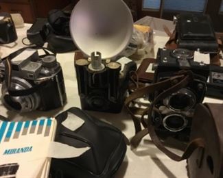 Downstairs- Table full of vintage cameras, binoculars, and movie cameras