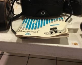 Downstairs- Table full of vintage cameras, binoculars, and movie cameras