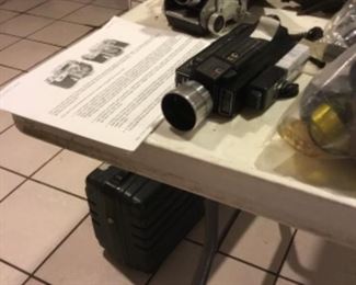 Downstairs- Table full of vintage cameras, binoculars, and movie cameras