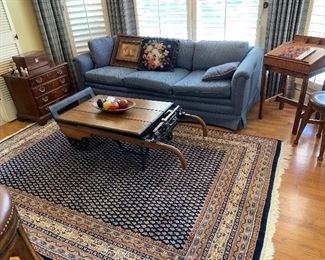 Clockwise: 7 ft. Blue Damask sofa, Antique Oak child's desk,  Hands of Wycombe Stool, Antique Renfrew mercantile cart & grain scale coffee table of solid wood and cast iron on a approx 6' x 9' Indian Mir/ Saraband rug, 50 years old & exc condition. 