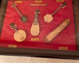 Shadow box of Chinese stringed instrument miniatures.