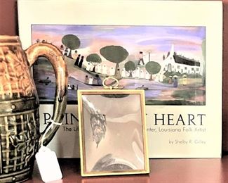 BOOK (behind the frame): "Painting by Heart: The Life and Art of Clementine Hunter, Louisiana Folk Artist" by Shelby R. Gilley