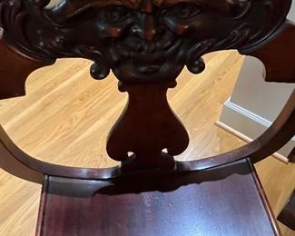 Another view of the antique chair showing face carved on the back