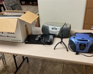 Vintage boom boxes and possibly old records in the cardboard box.