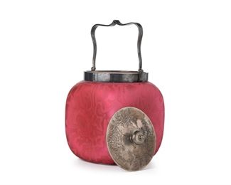 3202
A Victorian Art Glass Biscuit Barrel
Late 19th/Early 20th Century
Possibly by Thomas Webb, the red mother-of-pearl glass jar with square body and concave sides decorated with a free-form pattern and fitted with a sliver-plated lid and handle
8.5" H x 5" W x 5" D
Estimate: $300 - $400