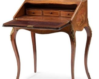 3232
A French Drop-Front Bureau De Dame
First-Quarter 20th Century
The bombe-style bureau de dame with scenic marquetry cartouches and openwork gilt-bronze gallery rail over a locked drop-front with inset leather writing surface and a fitted interior containing three drawers and a long pigeonhole atop a retractable compartment raised on gilt-bronze mounted cabriole legs with sabots
37" H x 30.25" W x 19.25" D
Estimate: $800 - $1,200
