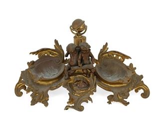 3344
A French Gilt-Bronze Inkwell
Fourth-Quarter 19th Century
With rocaille motifs centering two putti with a scroll and a globe flanked by two shell-form wells
7.75" H x 14.25" W x 7.625" D
Estimate: $300 - $500