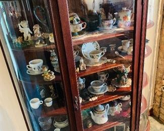 curved  front  curio  cabinet  and large  tea cup and tea pot collection