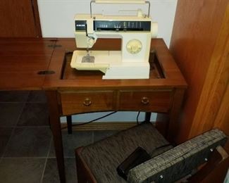 Singer sewing machine in wooden cabinet and chair