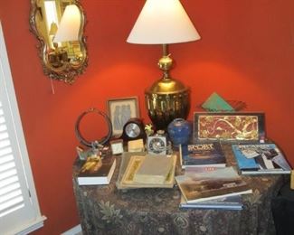 Nice & convenient multi-use particle board table that easily breaks down when not in use. Vintage Stiffel solid brass lamp, Vintage Gold & wood ornate mirror, Antique Chinese carved relief on wood, African tribal necklace on a stand.