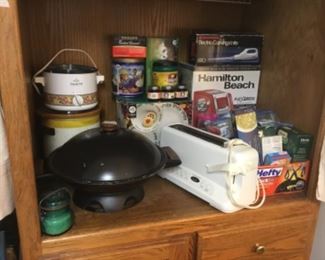 Middle of cabinet - more small appliances including Cuisinart toaster, Wok, electric knife, and crock pots