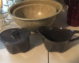 A large dark pottery serving bowl, Melmac nesting bowls and Melmac cream and sugar set.