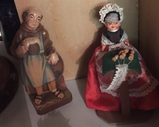 A beautifully carved man enjoying a beer and a little miss with lace-making supplies.