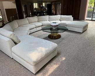 Very large off white vintage sectional that has been well cared for and recovered (additional fabric included). This can be used as shown in your large gathering room or separated to fit your space. There are 4 angled 2-seat sections and 2 ottomans. Seats are 37"D x 23"H. As shown, this measures 13'7" wide x 9'10" deep.