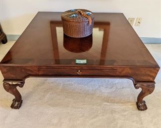 Wonderful banded mahogany square coffee table, by Baker, with pull-out candle tray and carved feet.