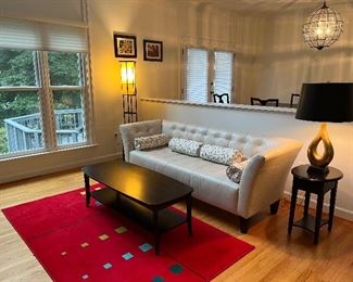 Chateaux D'ax white leather sofa with black rectangular rounded corner coffee table & two matching 1 drawer end tables atop a red geometric carpet by Galactic